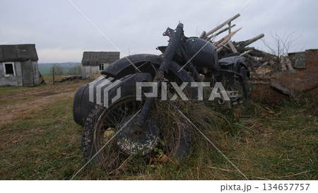 charred motorcycle debris scattered across rural landscape emphasizing violence, burned motorcycle wreckage with warped frame and scorched rubber highlighting past violence in rural setting charred motorcycle debris scattered across rural landscape emphasizing violence, burned motorcycle wreckage with warped frame and scorched rubber highlighting past violence in rural setting 134657757
