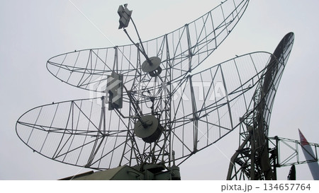 cluster radar dishes pointing skyward. overlapping parabolic grids and metal reflectors form layered silhouettes against pale sky, antenna mounts and electronics boxes visible, sense of scale 134657764