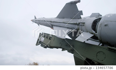 close perspective of rail-launched missile and launcher assembly fixed to wing pylon, green painted support strut, aerodynamic fins visible, cloudy sky and service equipment hinting at armory close perspective of rail-launched missile and launcher assembly fixed to wing pylon, green painted support strut, aerodynamic fins visible, cloudy sky and service equipment hinting at armory 134657786