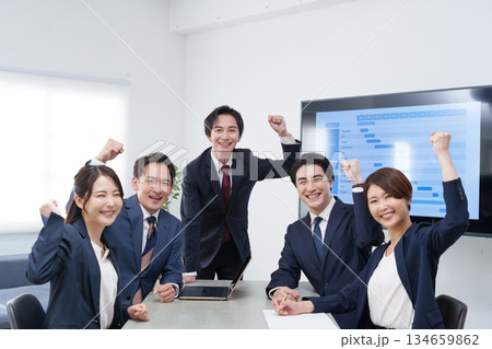 オフィスで会議するビジネスマン男女のガッツポーズ 134659862