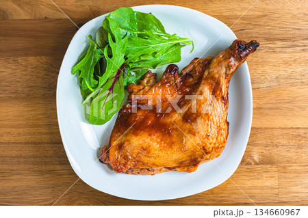 木目テーブルに白い皿で盛り付けたローストチキン 134660967