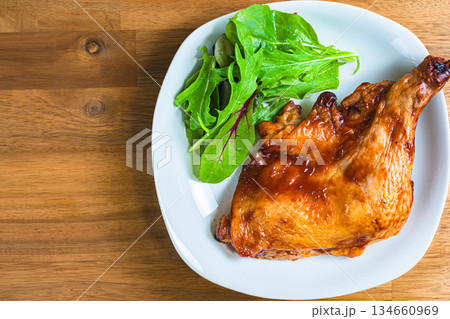 木目テーブルに白い皿で盛り付けたローストチキン 134660969