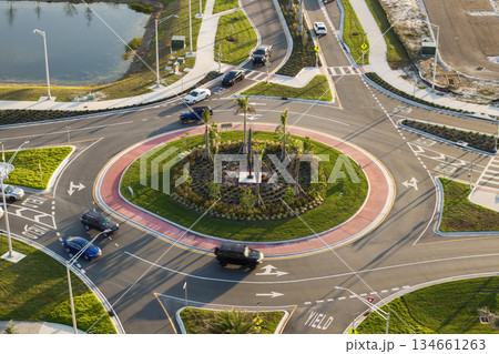 Traffic infrastructure in USA. Road roundabout intersection with driving cars. Circular transportation crossroads in Florida Traffic infrastructure in USA. Road roundabout intersection with driving cars. Circular transportation crossroads in Florida 134661263
