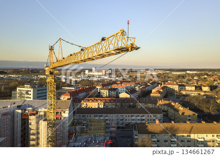 Tower crane on bright blue sky copy space background, city landscape stretching to horizon. Drone aerial photography. 134661267