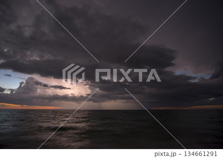 Thunderstorm clouds over rough ocean waters. Evening sea waves crushing on sandy beach. Beautiful seascape at sunset 134661291