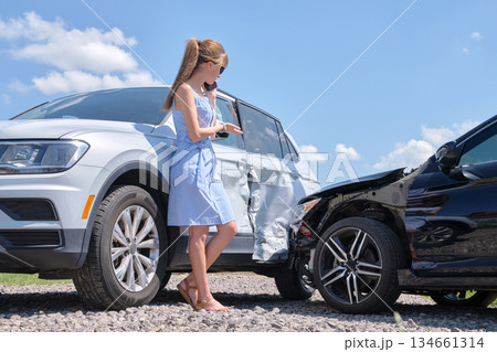 Stressed woman driver talking on mobile phone on street side calling for emergency service after car accident. Road safety and insurance concept 134661314