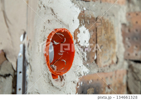 Socket orange boxes with wires in a wall. Cabling installation of electrical wires sticking out from electrical sockets hole on brick wall. Socket orange boxes with wires in a wall. Cabling installation of electrical wires sticking out from electrical sockets hole on brick wall. 134661328