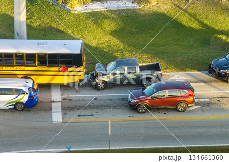 School bus and car accident on American street. Emergency services helping victims of vehicle crash on road in USA 134661360