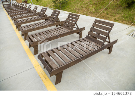 Row of empty wooden beach chairs near water outdoors. Row of empty wooden beach chairs near water outdoors. 134661378