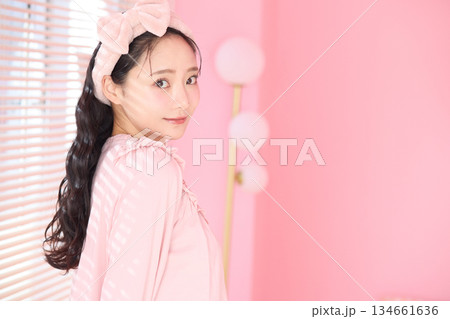 ピンクの部屋の窓際に立つ若い女性の美容ポートレート 134661636