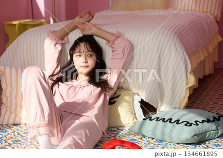 カラフルなベッドルームでリラックスする若い女性のかわいいポートレート	 134661895