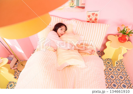 カラフルなベッドルームでリラックスする若い女性のかわいいポートレート	 134661910