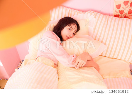 カラフルなベッドルームでリラックスする若い女性のかわいいポートレート カラフルなベッドルームでリラックスする若い女性のかわいいポートレート 134661912