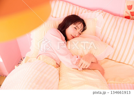 カラフルなベッドルームでリラックスする若い女性のかわいいポートレート カラフルなベッドルームでリラックスする若い女性のかわいいポートレート 134661913