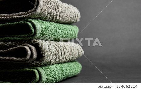 Stack of Soft Cotton Towels in Green and Grey on Dark Background with Copy Space. High quality photo Stack of Soft Cotton Towels in Green and Grey on Dark Background with Copy Space. High quality photo 134662214