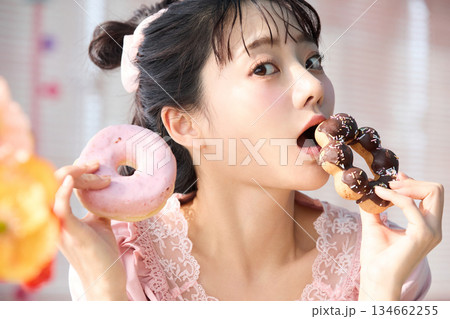 カラフルな部屋でドーナツを食べるかわいい女性のポートレート 134662255
