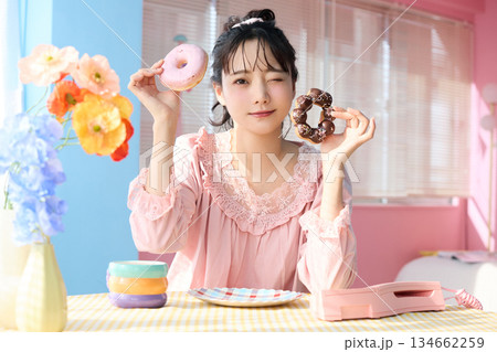 カラフルな部屋でドーナツを食べるかわいい女性のポートレート 134662259