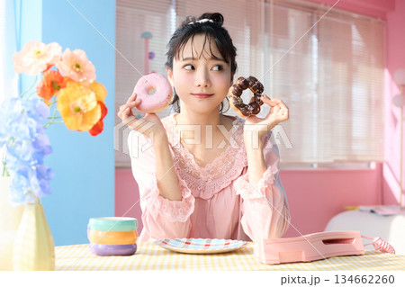 カラフルな部屋でドーナツを食べるかわいい女性のポートレート 134662260