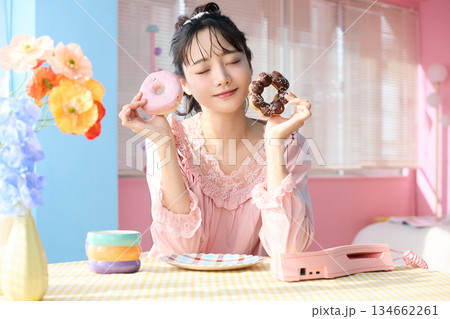 カラフルな部屋でドーナツを食べるかわいい女性のポートレート 134662261