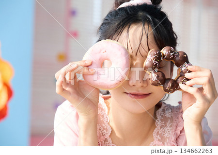 カラフルな部屋でドーナツを食べるかわいい女性のポートレート カラフルな部屋でドーナツを食べるかわいい女性のポートレート 134662263