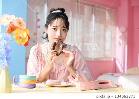 カラフルな部屋でドーナツを食べるかわいい女性のポートレート カラフルな部屋でドーナツを食べるかわいい女性のポートレート 134662273