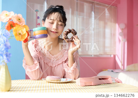 カラフルな部屋でドーナツを食べるかわいい女性のポートレート カラフルな部屋でドーナツを食べるかわいい女性のポートレート 134662276
