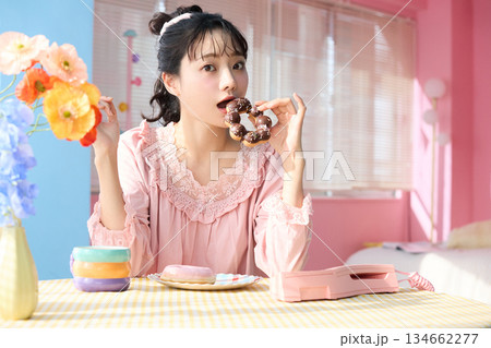 カラフルな部屋でドーナツを食べるかわいい女性のポートレート 134662277