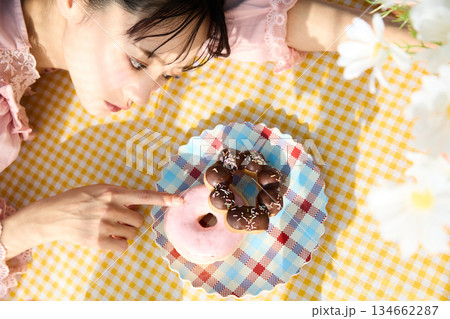 カラフルな部屋でドーナツを食べるかわいい女性のポートレート カラフルな部屋でドーナツを食べるかわいい女性のポートレート 134662287