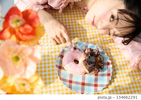 カラフルな部屋でドーナツを食べるかわいい女性のポートレート 134662291