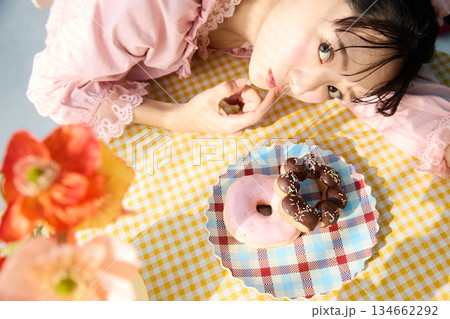 カラフルな部屋でドーナツを食べるかわいい女性のポートレート 134662292