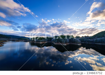 水不足の奈良布目ダム師走の夕景　大空を渡る雲と西に傾いた夕日に照らされる布目湖⑦ 134663732