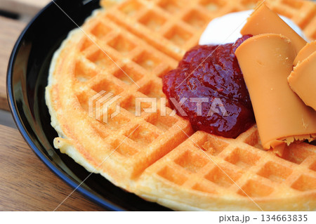 イチゴジャムとクリーム、ブラウンチーズが添えられたおいしそうな薄焼きの北欧風ワッフル 134663835