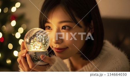 ガラスのスノードームを両手で持つ女性 134664030