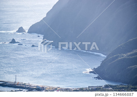 断崖絶壁の海岸線を飛ぶ旅客機　八丈島のダイナミックな空と海の風景 134666887