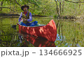 Cowboy in a canoe floats on the river in the forest 134666925
