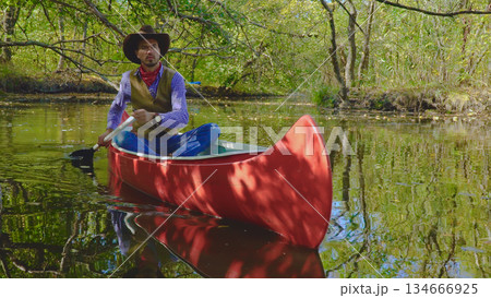 Cowboy in a canoe floats on the river in the forest 134666925