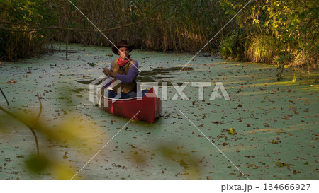 Cowboy in a canoe floats on the river 134666927