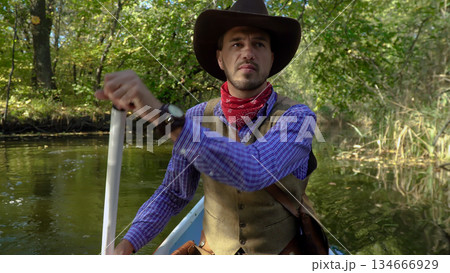 Cowboy in a canoe floats on the river in the forest 134666929