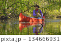 Cowboy in a canoe floats on the river in the forest 134666931