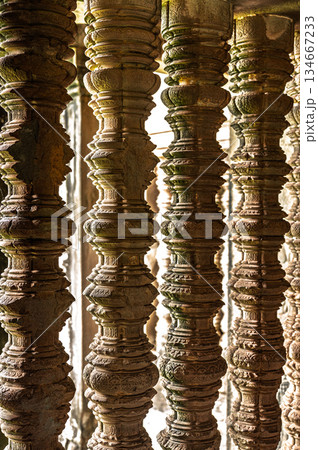 Ancient stone window pillars balusters close up temple architecture detail geometric shape light shadow historic structure archaeology Khmer design decoration texture vertical 134667233