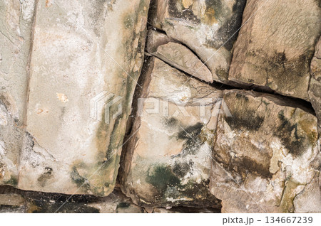 Close up texture background of cracked and weathered ancient stone wall blocks with green moss details in Cambodia temple 134667239