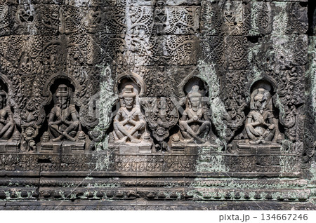 Intricate stone bas relief carvings of seated figures on ancient wall of terrace of leper king in angkor thom 134667246