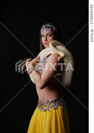 Woman performs dance holding a snake in a dark space during a live event 134668448