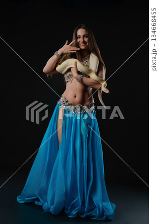 Woman dances with snake in a studio at night during a performance Woman dances with snake in a studio at night during a performance 134668455