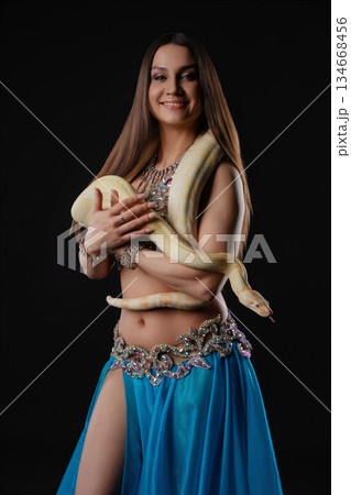 Woman dances with a snake in a dark setting showcasing movement and connection Woman dances with a snake in a dark setting showcasing movement and connection 134668456