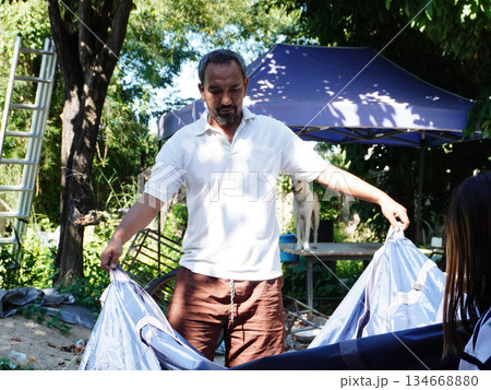 Father and Daughter Working Together to Pack Up Camping Tent. 134668880