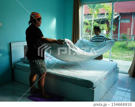 Mother and Daughter Making Bed Together in a Bright Bedroom. 134668910