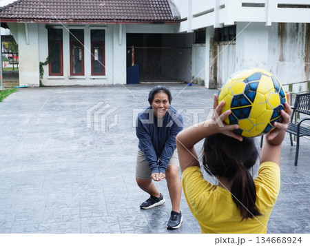 Mother and Daughter Playing Volleyball and Passing Ball Outdoors with Fun 134668924