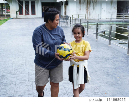 Mother and Daughter Playing Volleyball and Passing Ball Outdoors with Fun 134668925