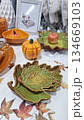 Artistic autumn-inspired ceramic dishes and pumpkin-shaped bowls displayed on a decorative table 134669103